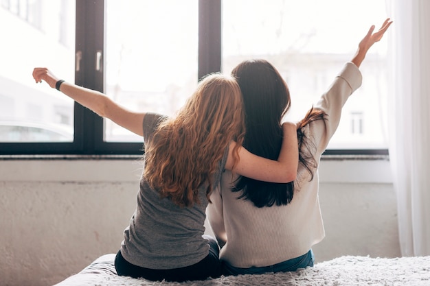 Young women hugging on bed