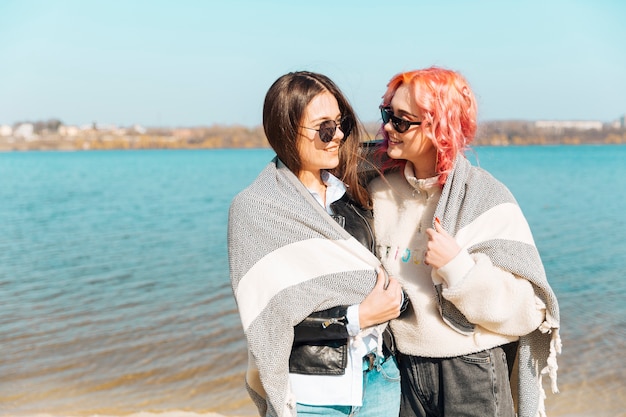 Free photo young women hugging and covering with blanket