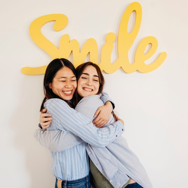 Young women hugging near smile writing