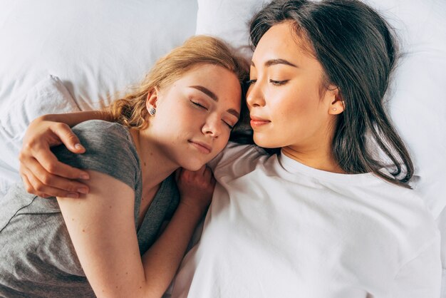 Young women hugging sleeping girlfriend