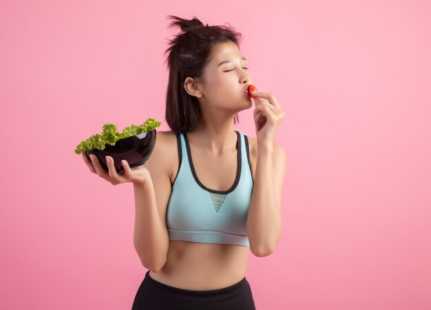 Young women like to eat vegetables on a pink.