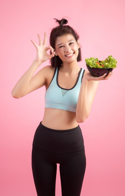 Young women like to eat vegetables on a pink.