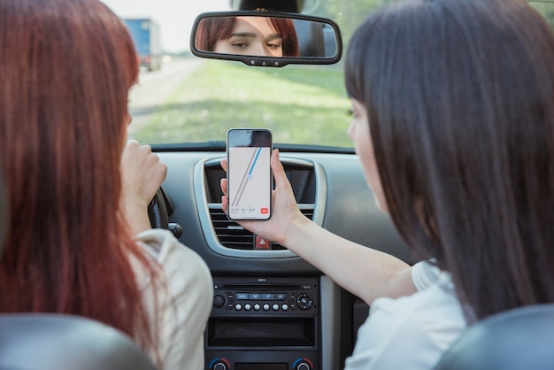 Young women looking at smartphone in car