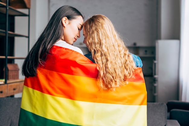 Young women in love covering in rainbow flag