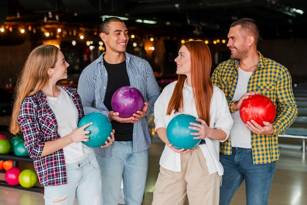 Young women and men holding colorful bowling balls