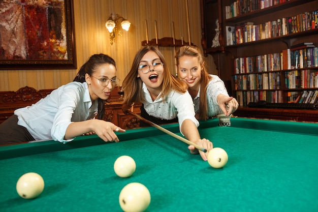 Young women playing billiards at office after work.