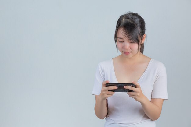 Young women playing on phones in gray wall