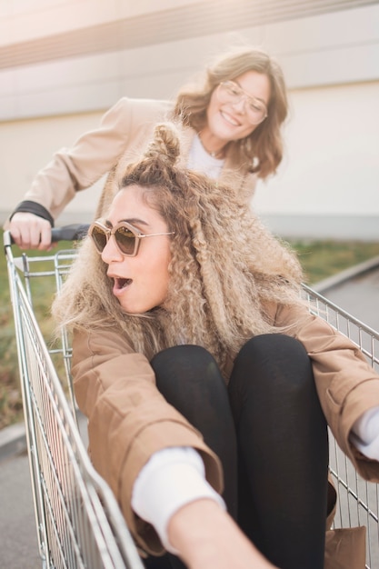 ショッピングカートで遊ぶ若い女性