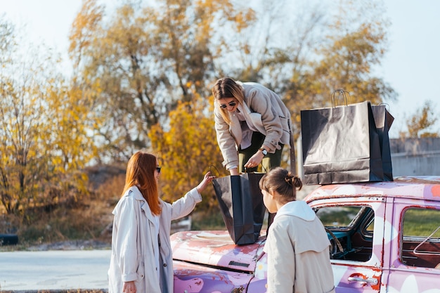 Young women posing near an old decorated car