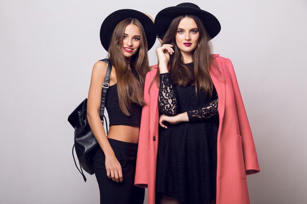 Young women posing and wearing stylish black hats
