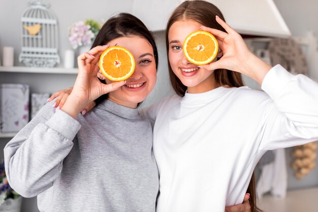 Young women posing with halves of oranges