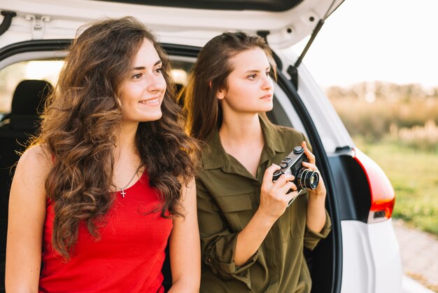 Young women taking pictures near car