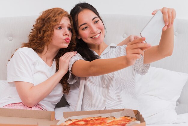 피자를 먹는 동안 셀카를 복용하는 젊은 여성