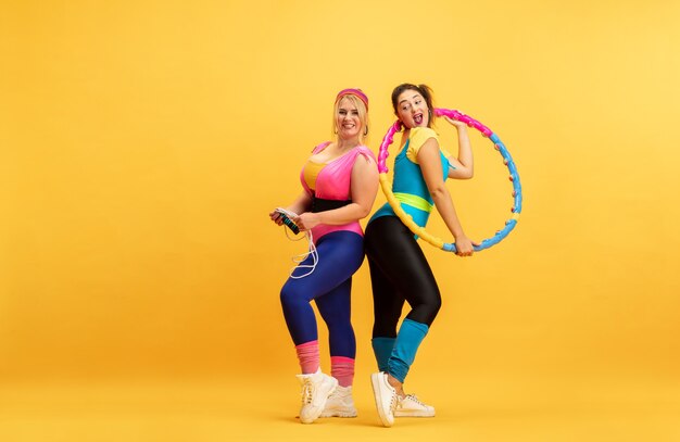 Young women training on yellow wall