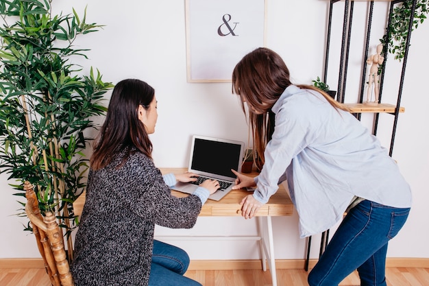 Free photo young women using laptop at table