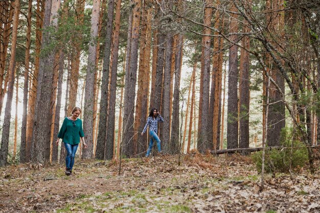 숲에서 나무 옆에 걷는 젊은 여성