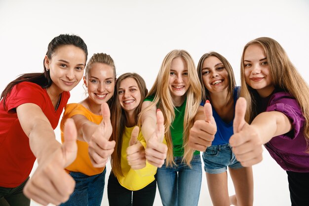 Young women weared in LGBT flag colors isolated on white wall. Caucasian female models in bright shirts.