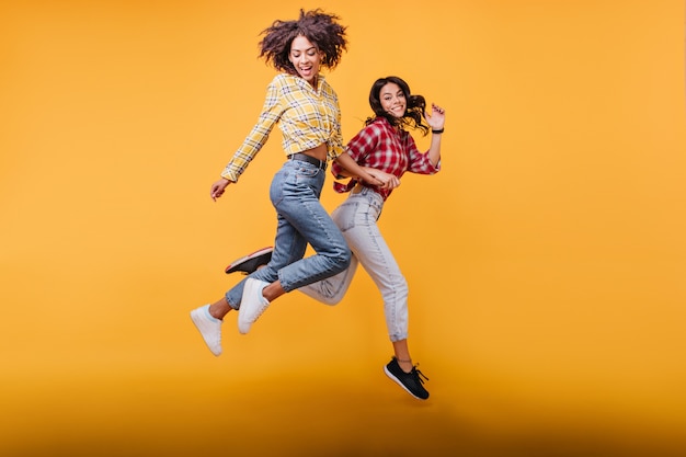 Young women with curly hair run. Models in streetwear posing in jump