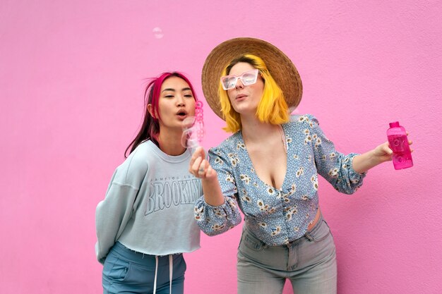 Young women with dyed hair near pink wall