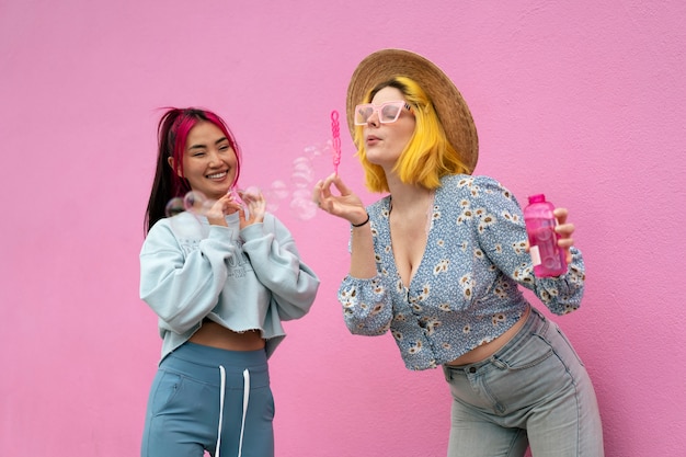 Young women with dyed hair near pink wall