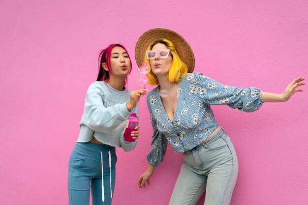 Young women with dyed hair near pink wall