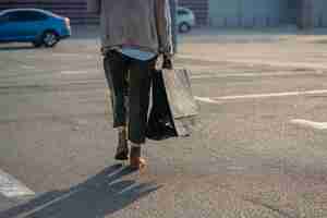 無料写真 通りを歩いている買い物袋を持つ若い女性。