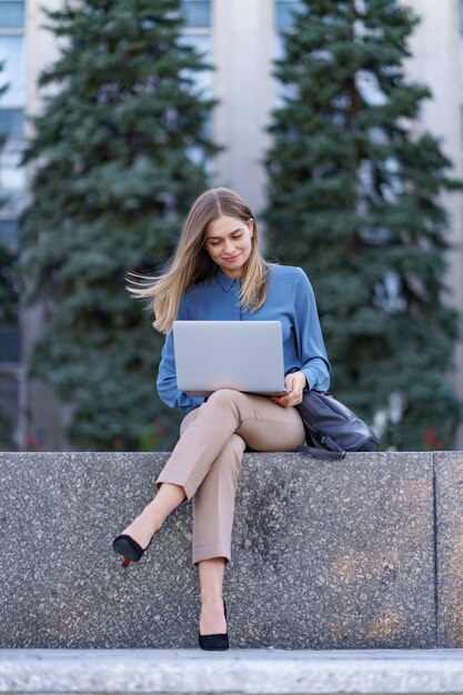 Young women working on laptop in the city square