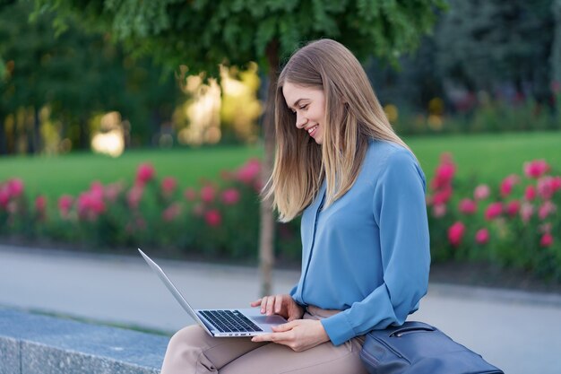 Young women working on laptop in the city square