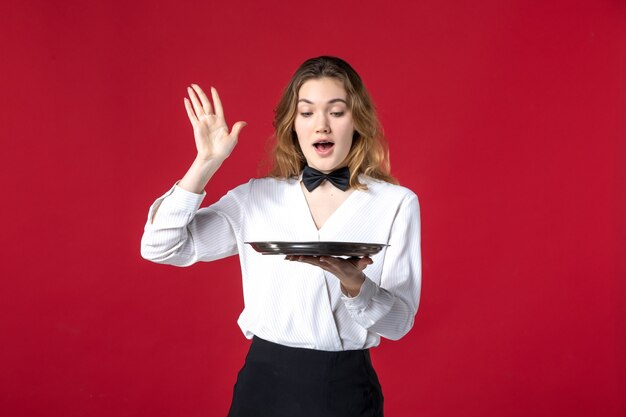 young wondering waitress woman butterfly on the neck and holding tray on red background