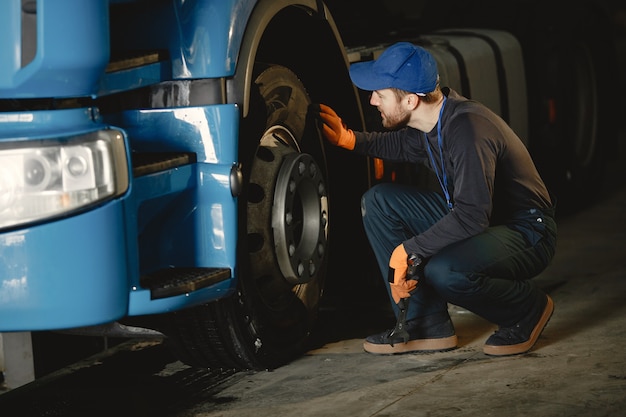 A young worker checks wheel. Truck malfunction. Service work.