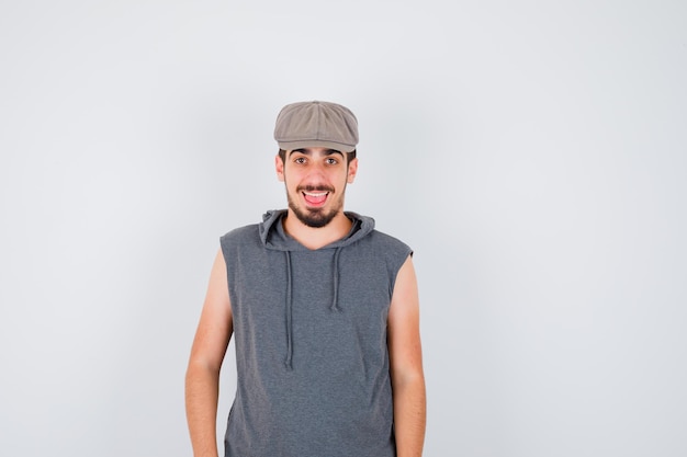 Young worker standing straight and posing at front in gray t-shirt and cap and looking happy