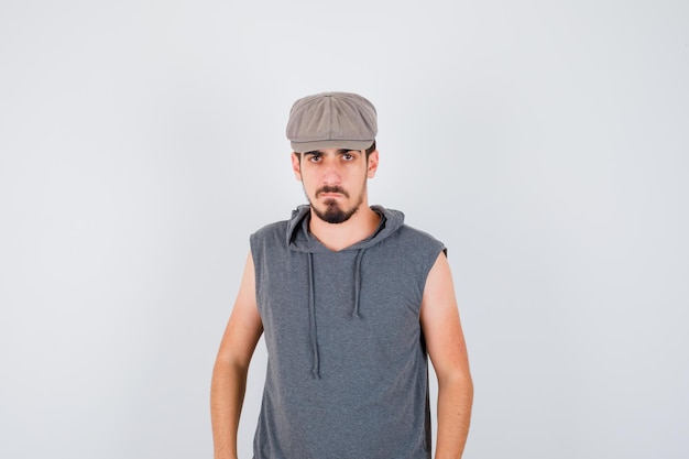 Free photo young worker standing straight and posing at front in gray t-shirt and cap and looking serious