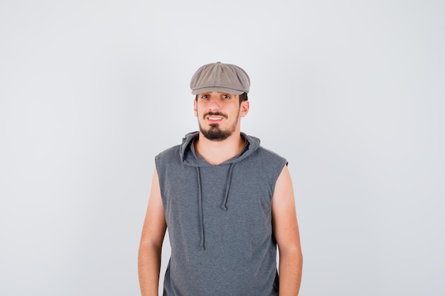 Young worker standing straight and smiling in gray t-shirt and cap and looking happy