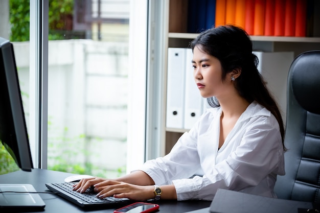 Free photo young working woman typing on keyboard computer