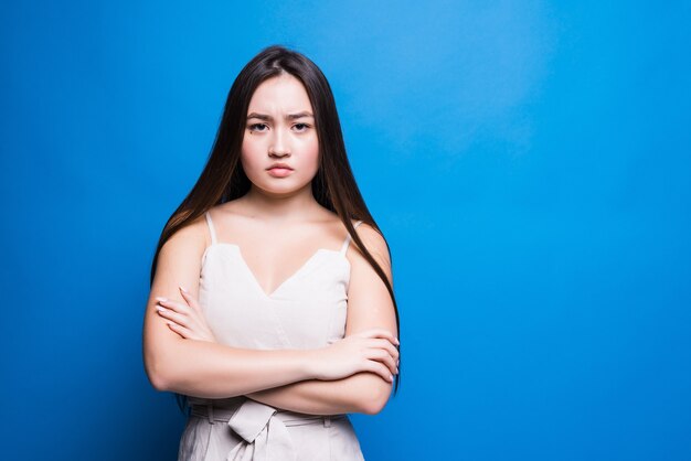 Young worried asian woman isolated on blue wall