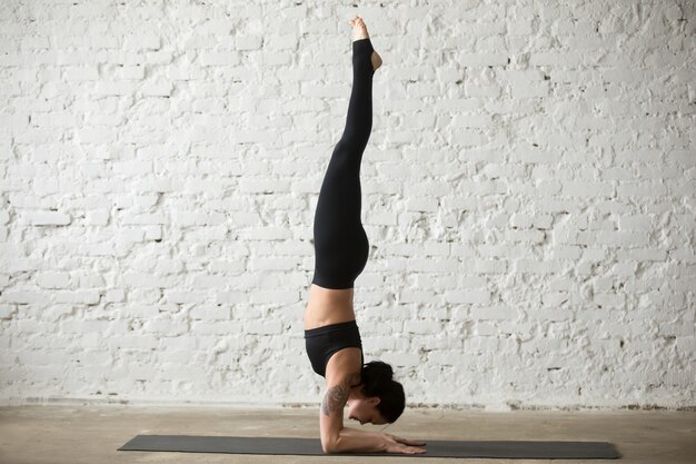 young yogi attractive woman in pincha mayurasana pose, loft back