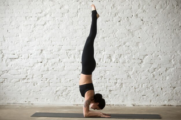 Young yogi attractive woman in Pincha Mayurasana pose, loft back