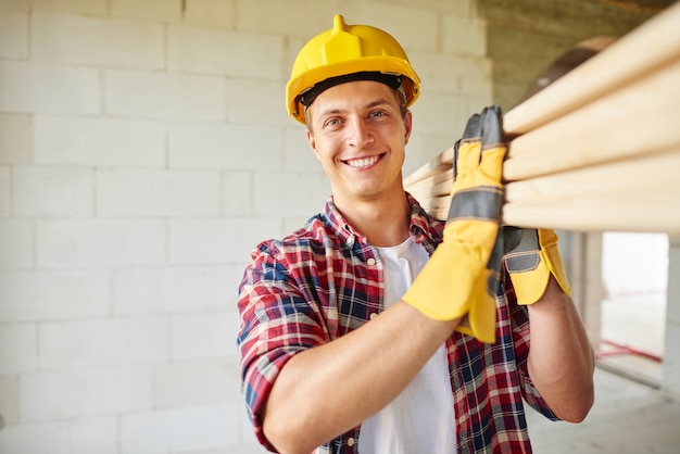 Free photo younger carpenter holds wooden planks