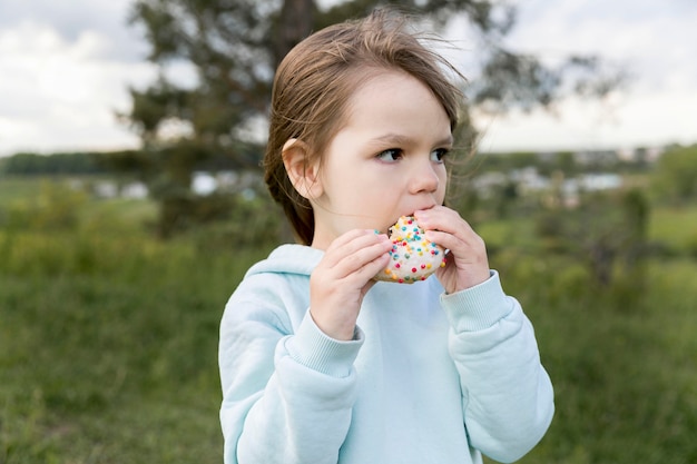 Free photo youngster outdoors eating a doughnut