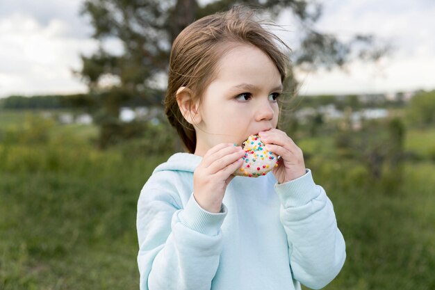 Youngster outdoors eating a doughnut