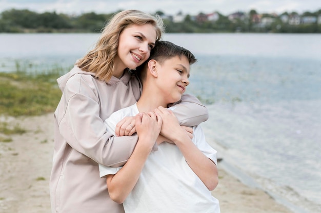 Мальчик на улице и мама обнимаются на берегу озера