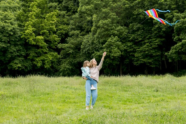 Youngster outdoors and mom playing with kite