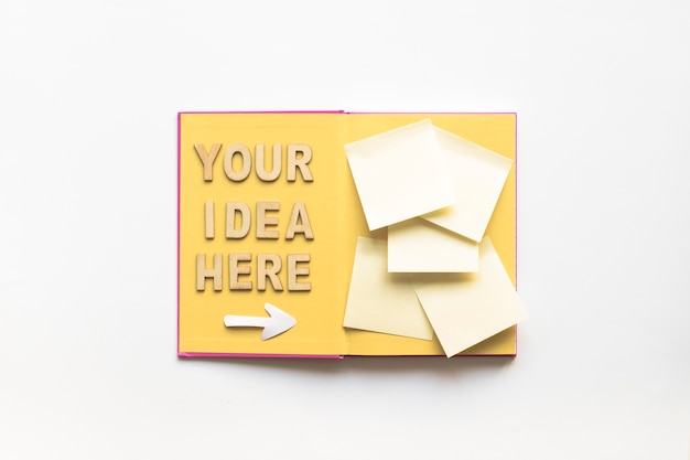 Your idea here text with arrow symbol directing towards sticky notes on book