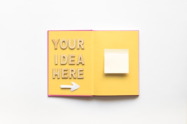 당신의 아이디어는 여기 책 위에 흰색 접착 메모를 보여주는 화살표 기호로 텍스트