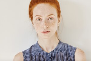 youth and tenderness. close up portrait of teenage girl with ginger hair and healthy skin with freckles wearing sleeveless shirt with spots
