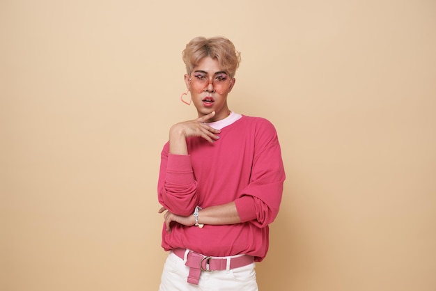 Youth asian transgender lgbt looking at camera while posing isolated over nude color background
