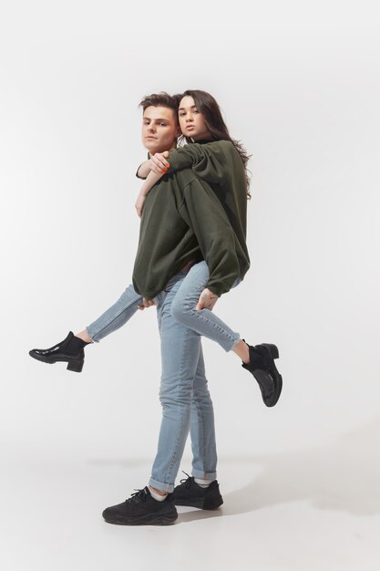 Youth. Trendy fashionable couple isolated on white  wall. Caucasian woman and man posing in basic minimal unisex clothes. Concept of relations, fashion, beauty, love. Inclusive.