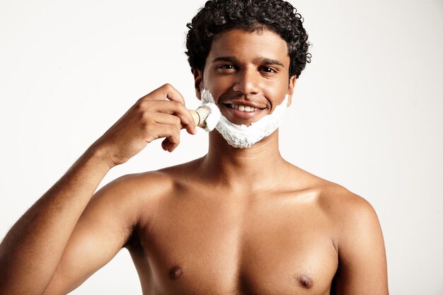 Ypung man puts foam for shave on face