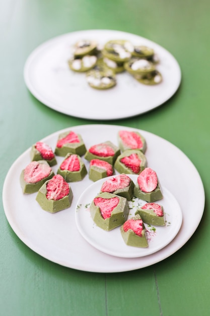 Yummy desserts with strawberry on white ceramic plates over green table