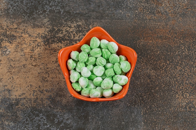 Yummy green menthol candies in orange bowl.